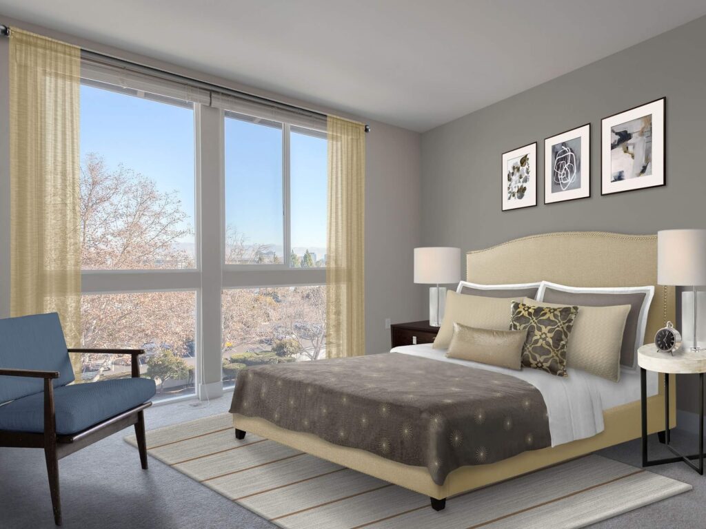Modern bedroom with large windows, beige and gray decor, a double bed with pillows, a blue armchair, side tables with lamps, and three framed artworks on a gray wall. Sunlight streams in from outside.