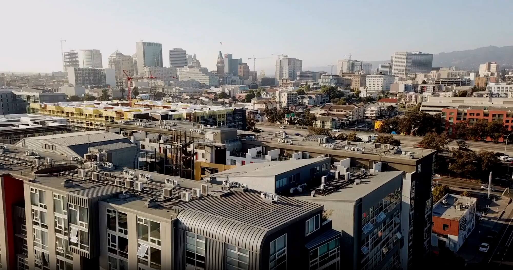 A cityscape view featuring modern apartment buildings in the foreground and a downtown skyline with high-rise buildings in the background under a clear sky.